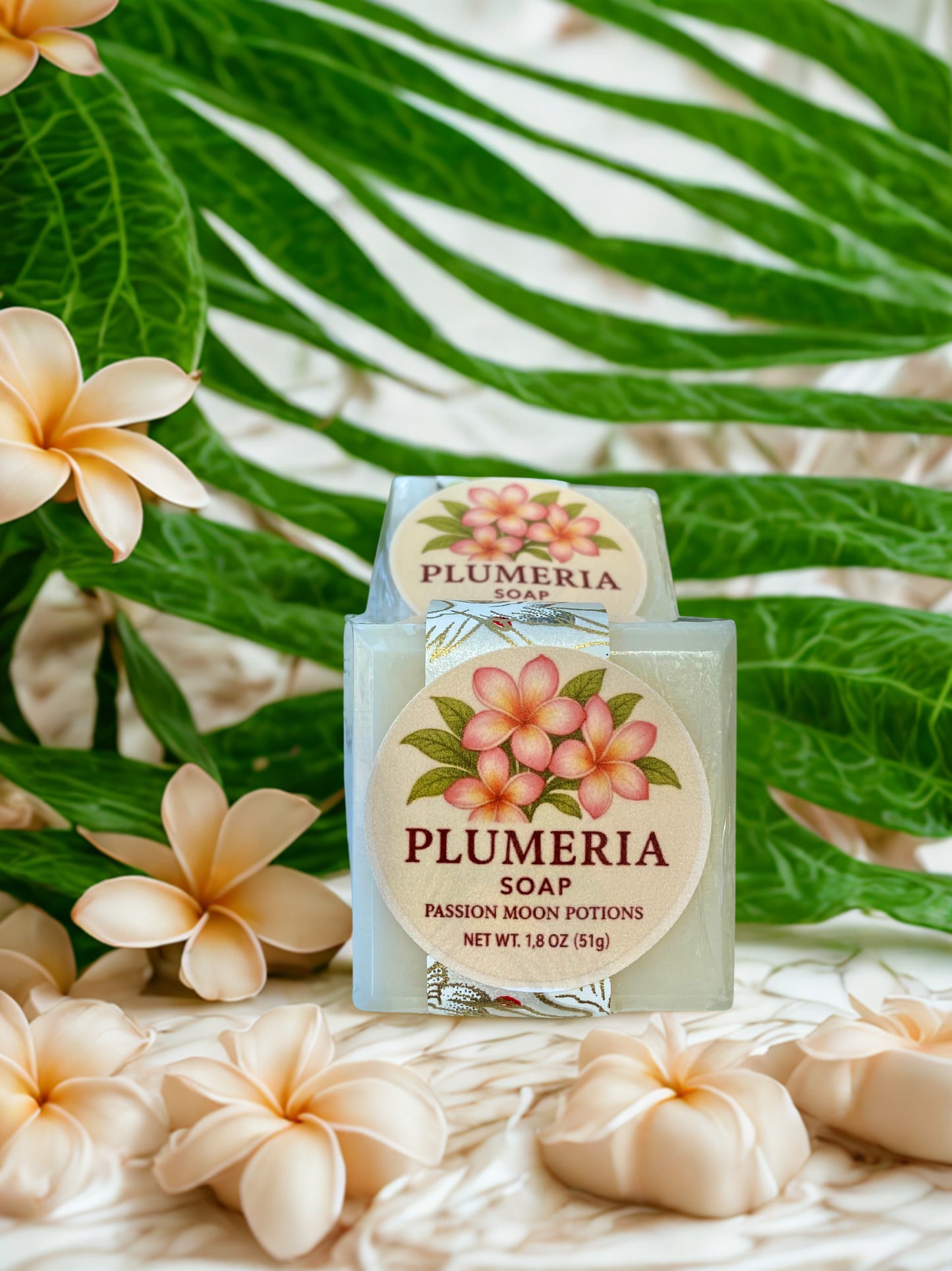 Plumeria soap with floral packaging against a green leafy background